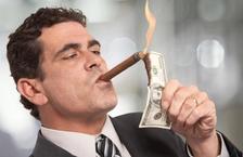 rich businessman lighting cigar with $100 dollar bill