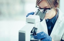female forensic scientist using microscope