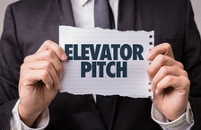 Closeup of businessman holding piece of paper saying 'elevator pitch'