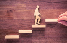 Hand placing wooden steps for wooden figure climbing stairs
