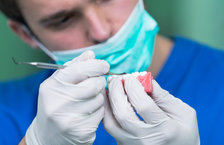 A close-up of an orthodontist working on a patient's dentures