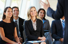 A group of smiling people listening to a speaker at a seminar