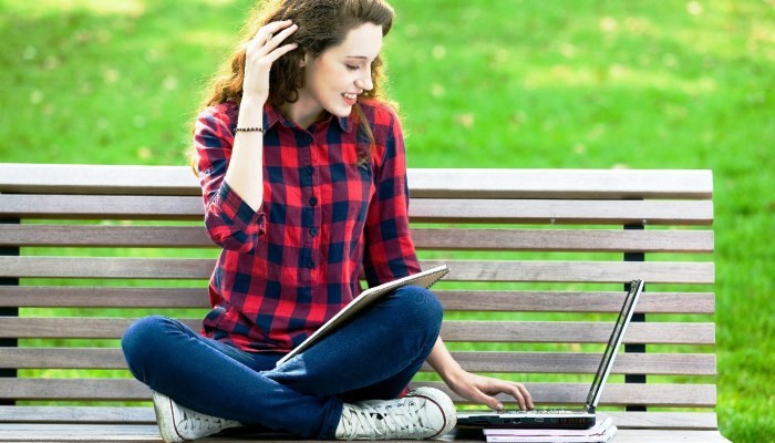 woman sitting on bench using laptop
