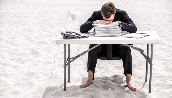 man sitting at desk in sand