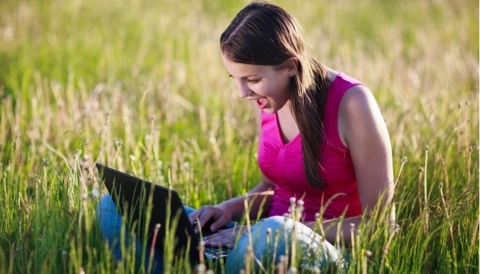 pretty young woman using her laptop computer outdoors