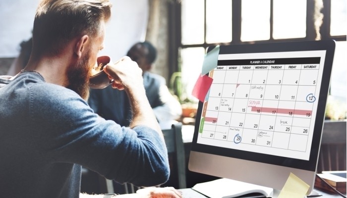 man drinking coffee using computer calender