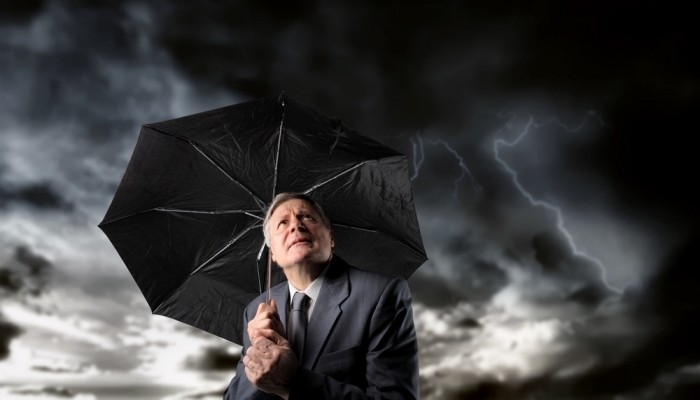 Businessman holding umbrella in storm