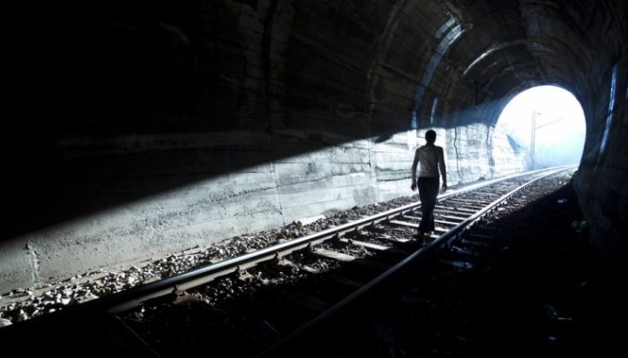 Silhouette walking towards end of tunnel