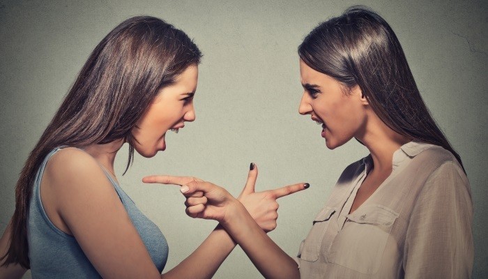 Two women pointing at each other