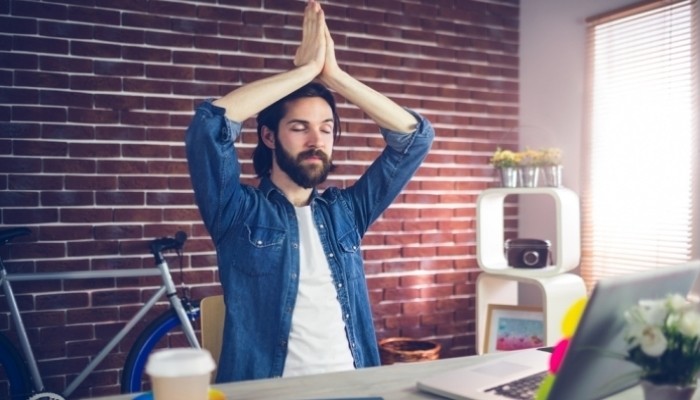 businessman with eyes closed meditating in creative office