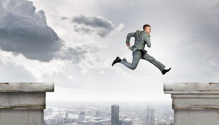 Businessman jumping over gap