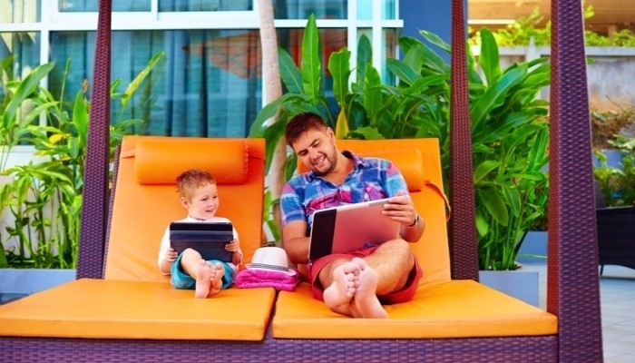 happy father and son busy with digital tablet on vacation