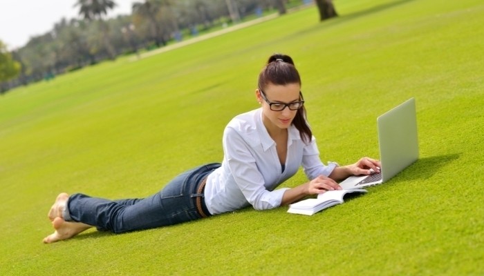 happy young student woman with laptop in city park study