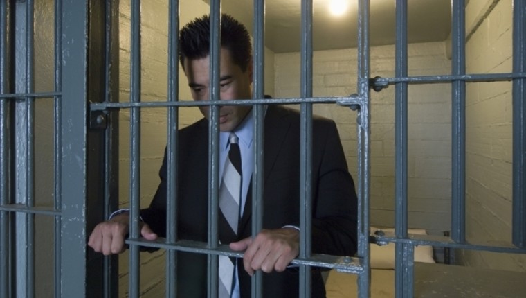 man standing behind bars
