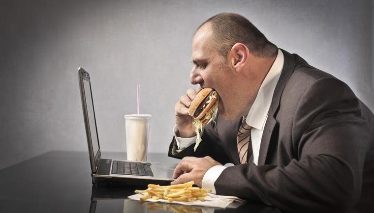 Businessman eating burger over laptop