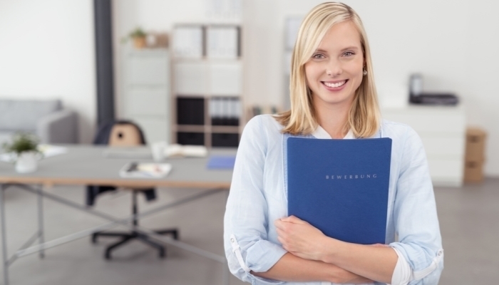 blond young woman hugging a blue documents folder