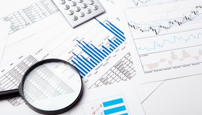 financial charts and graphs on the table with magnifying glass