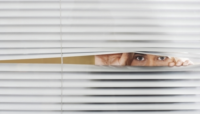 Woman peeking through blinds