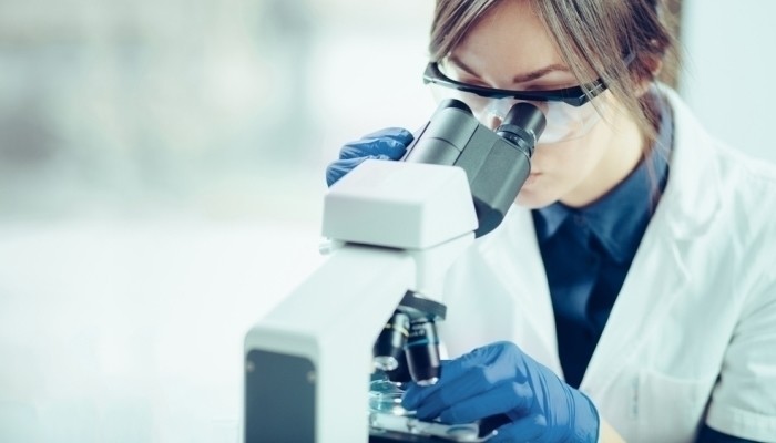 female forensic scientist using microscope