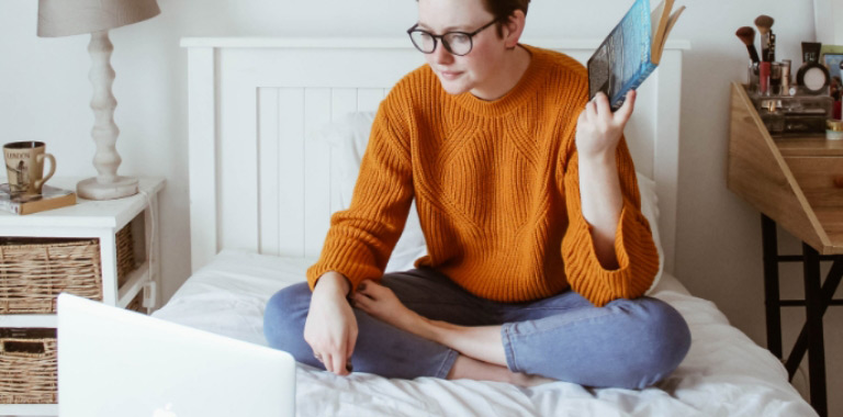 Woman sitting on a bed with laptop