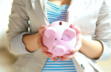 Young woman holding pink piggy bank