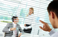 A manager watching two employees through window blinds