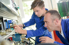 A mechanical engineer training a young apprentice