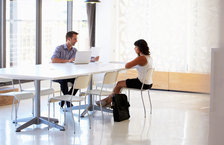A businessman interviewing a female applicant in a spacious meeting room